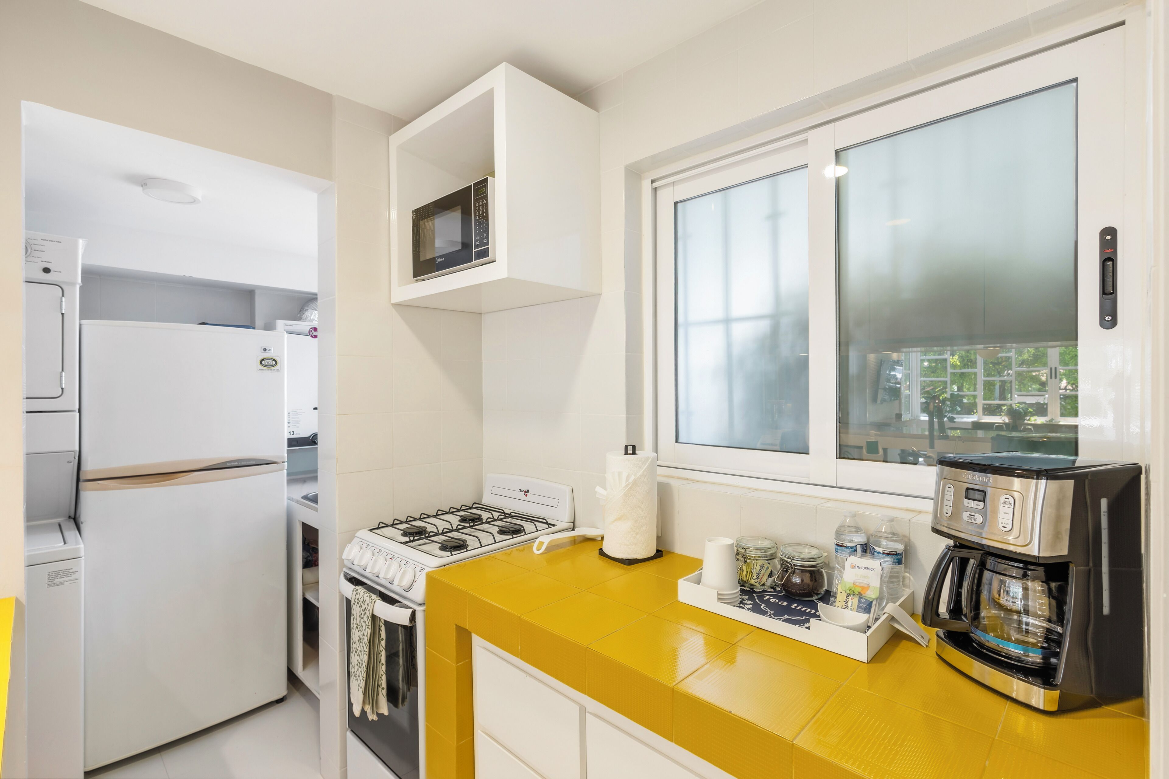 A modern kitchen with a gas stove, white appliances, a yellow countertop, and a coffee maker.