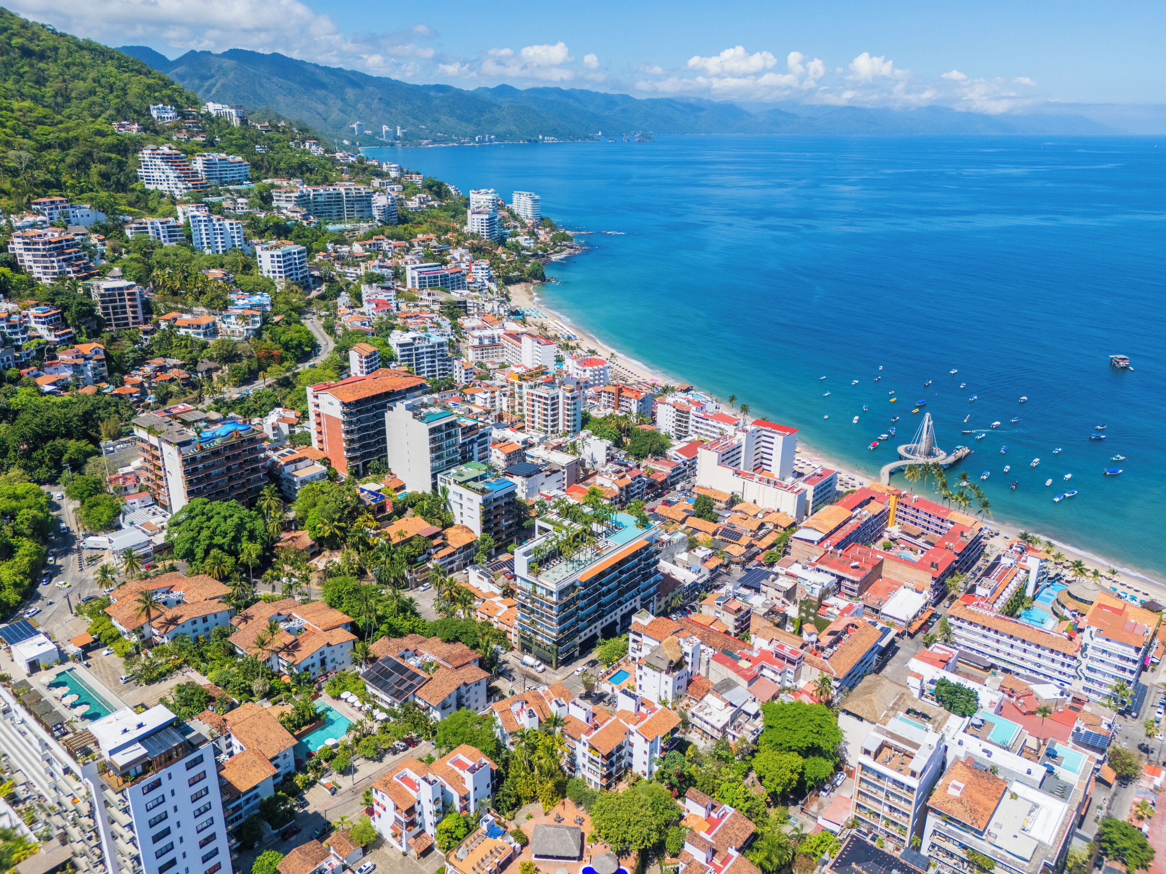 A coastal cityscape with dense urban development, a beach, and a clear view of the ocean.