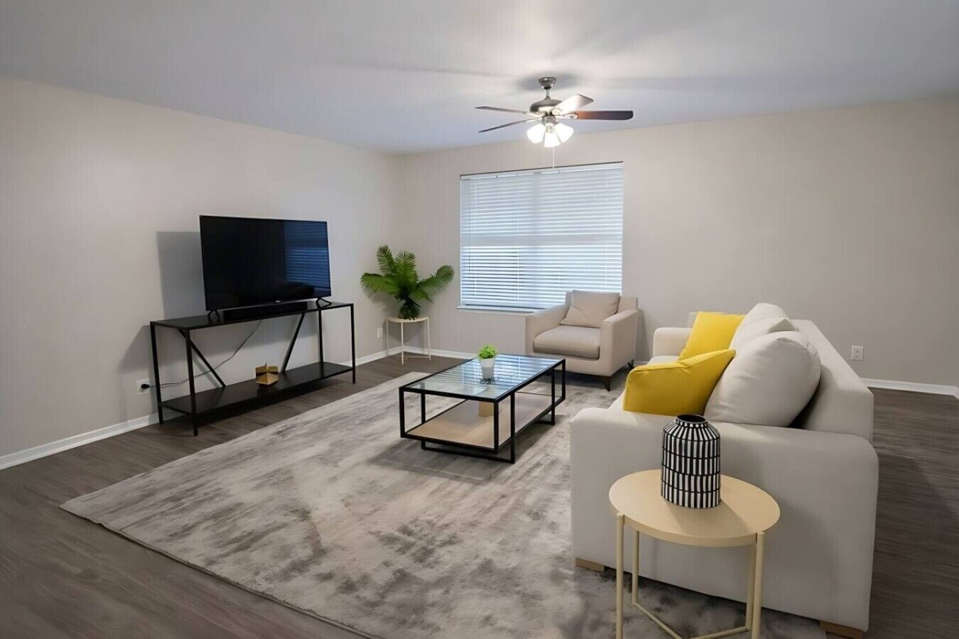 A living room with a TV, sofa, coffee table, and a ceiling fan.