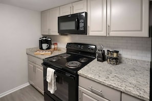 A kitchen with a black stove, a microwave above it, and a coffee maker on the counter.