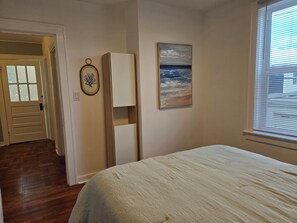 Een slaapkamer met een bed, een deur, een wandkast en een schilderij.