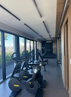 Ein Fitnessraum mit Cardiogeräten, Langhantelbänken und Kurzhanteln.