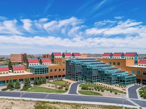 A modern building with multiple red-roofed sections, a central glass structure, and a landscaped courtyard. - Ideal for Long Vacations & Rock Springs Stays | Rock Springs Arch - 2.2 miles (Rock Springs)