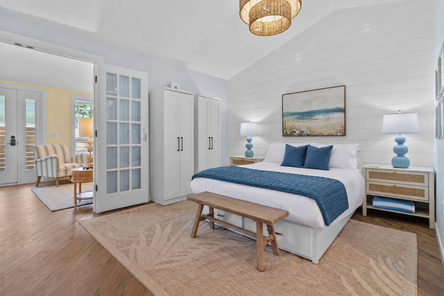 A bedroom with a bed, bedside tables, a bench, a door, and a window.