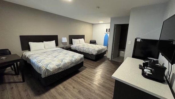 Une chambre d’hôtel avec deux lits, un bureau, une télévision et une kitchenette.