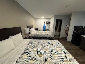 Una habitación de hotel con una cama grande, un escritorio, una silla, un armario y un televisor.