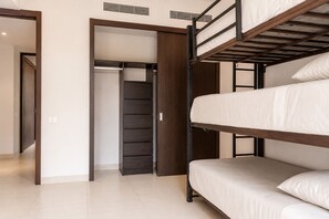 A bunk bed room with a wardrobe and a door leading to another room.