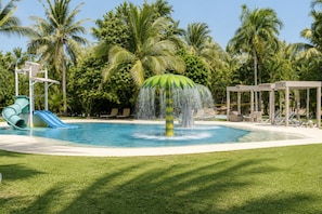 A swimming pool with a water feature, surrounded by palm trees and lounge chairs. - Luxury Family Resort & Beach Club  (Acapulco de Juárez)