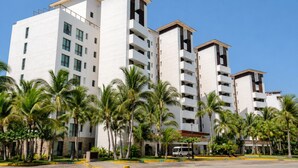 A multi-story hotel with a modern design, featuring balconies and a parking area with a van.