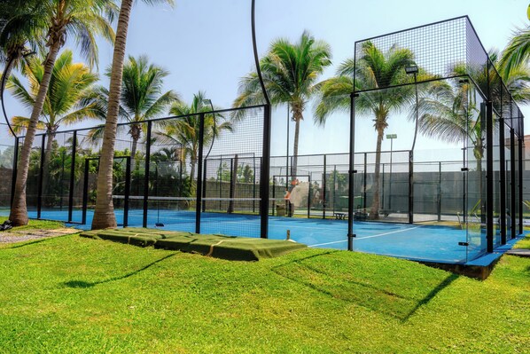 A tennis court with a net, surrounded by palm trees and a fence. - Luxury Family Resort & Beach Club  (Acapulco de Juárez)