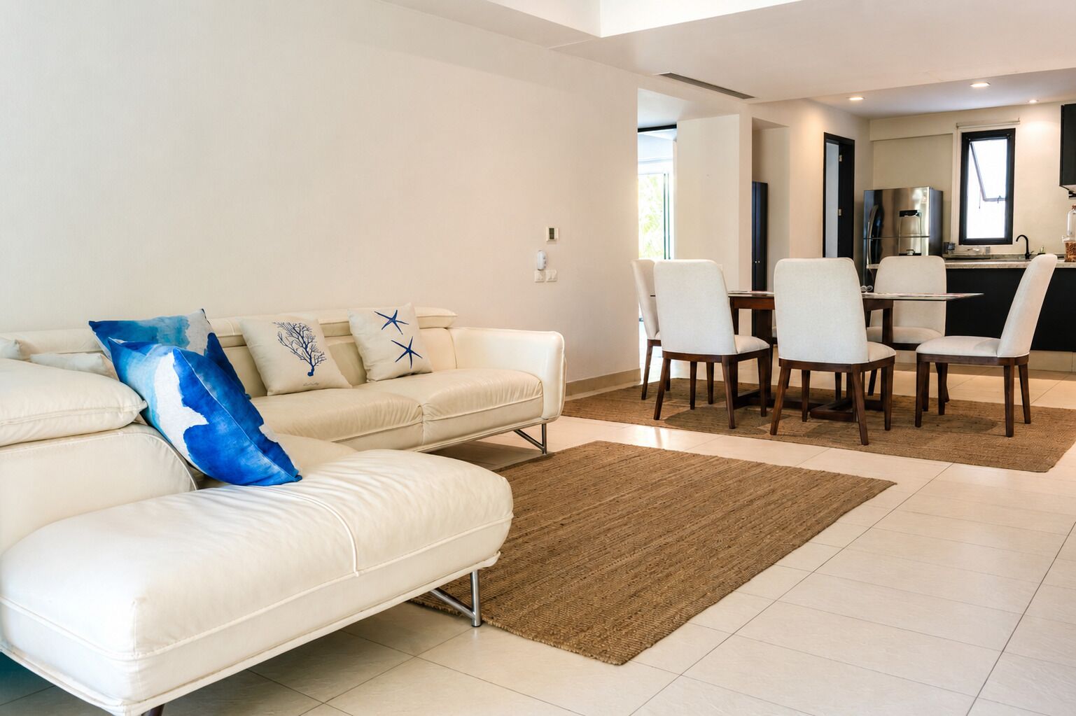 A modern living room with a sofa, chairs, and a dining table.