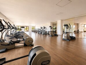 A spacious gym with multiple cardio machines and mirrors on the walls.