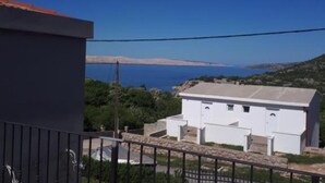 Un edifici blanc amb teulada plana, mur de pedra i barana metàl·lica al primer pla.