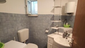 Et lille badeværelse med toilet, vask og et vindue.