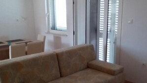 En stue med sofa, spisebord med stole og et vindue med persienner.