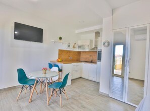 A compact kitchen with a wooden countertop, a sink, and a built-in oven. There is a dining area with a round table and four chairs. - One bedroom apartment with terrace (Kastel Luksic)