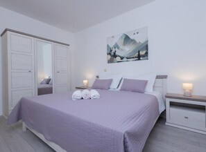 Ein Schlafzimmer mit einem Bett, einem Nachttisch, einem Kleiderschrank und einem Bild an der Wand.