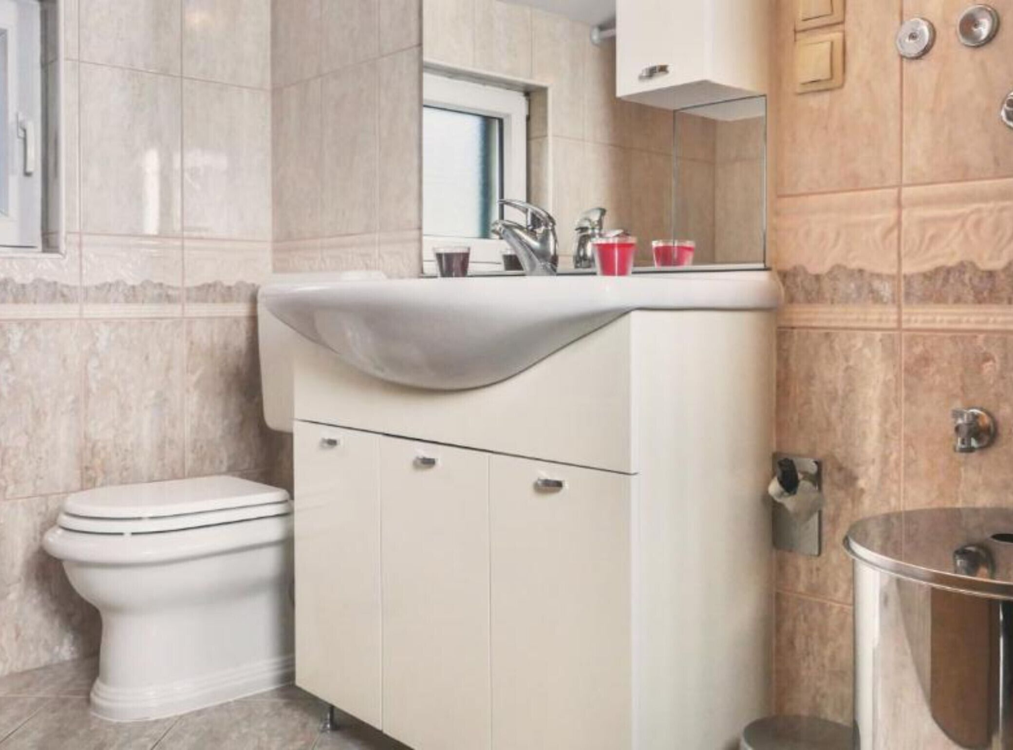 Ein Badezimmer mit Toilette, Waschbecken mit Spiegel und einem Schrank.