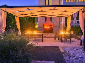 Eine Terrasse im Freien mit Feuerstelle, Sitzgelegenheiten und einer Pergola.