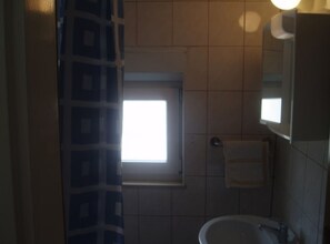 Et badeværelse med et vindue, en vask og en håndklædestang.