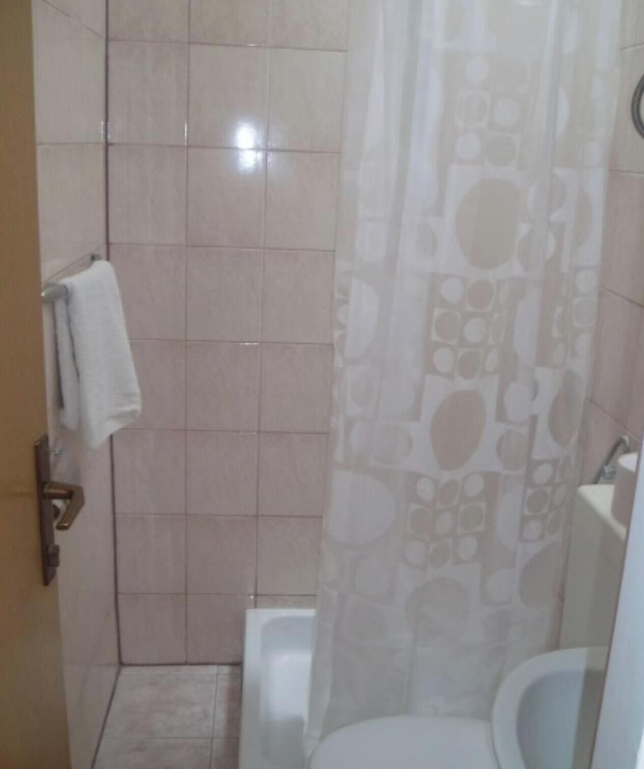 Un baño con ducha, inodoro y toallero.