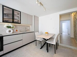 A modern kitchen with a dining area, featuring a countertop, sink, cabinets, and a table with chairs. - Apartment With Terrace And Balcony (Trpanj)