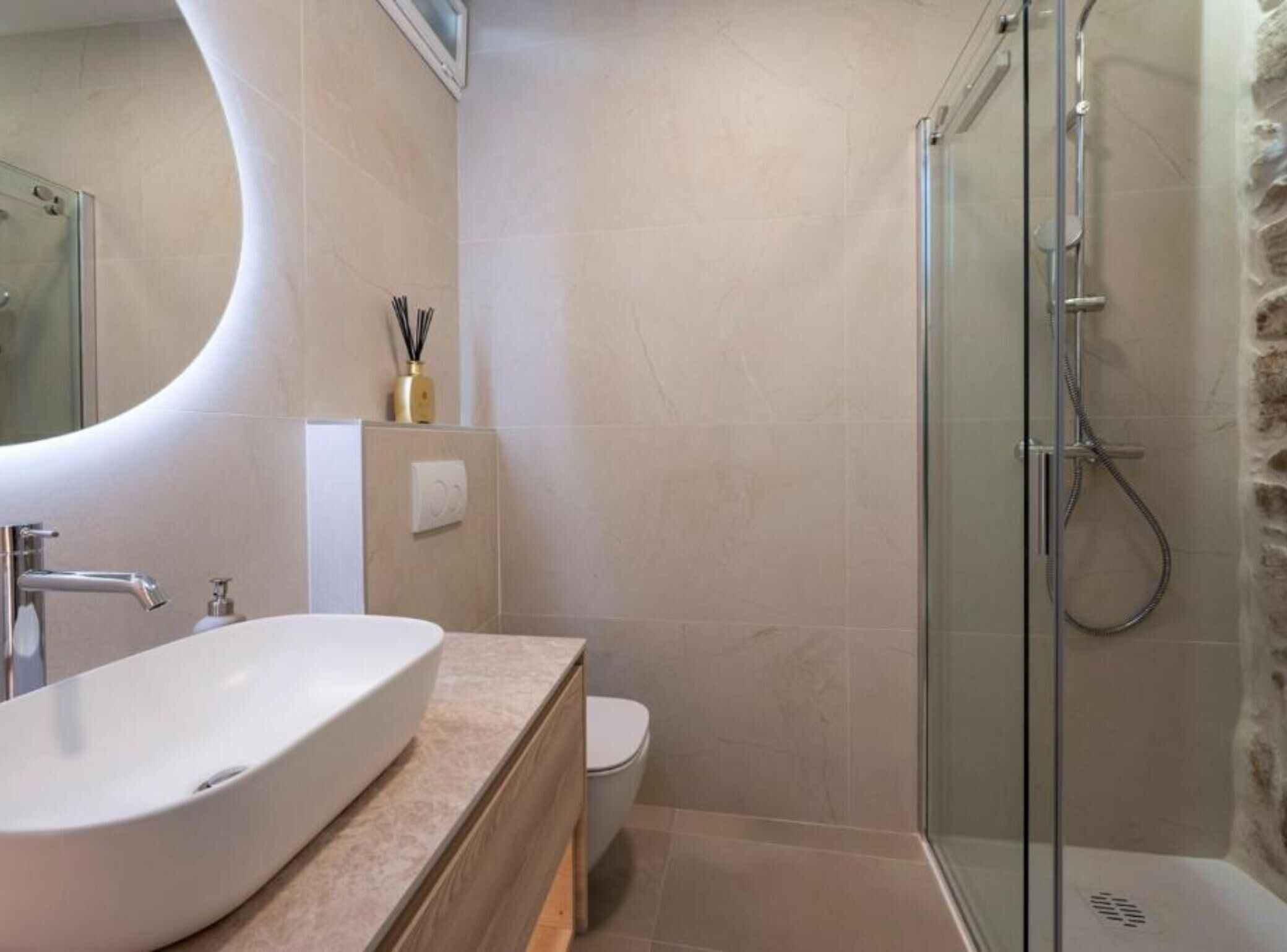 A bathroom with a large oval sink, a toilet, and a glass-enclosed shower.
