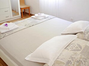 Ein Hotelzimmer mit Bett, Kissen, einem Sessel, einem Schrank und einem Fenster mit Vorhängen.