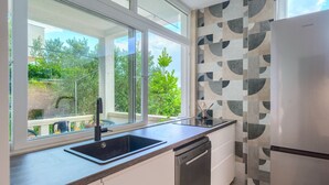 Eine moderne Küche mit großem Fenster, Geschirrspüler und Kühlschrank.