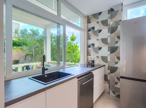 Eine moderne Küche mit großem Fenster, Geschirrspüler und Kühlschrank.