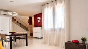 Uma sala de estar moderna com área de jantar, escada e uma parede com destaque em vermelho.