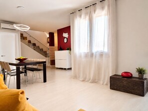 Ein modernes Wohnzimmer mit Essbereich, Treppe und einer roten Akzentwand.