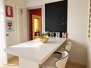 A modern kitchen with a white countertop, a bowl of fruit, and a blackboard with the word 'KITCHEN' and a heart symbol. - La Casa di Ale By Case al Lago (Lonato)