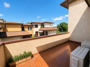 Ein Wohnbalkon mit Fliesenboden, einem Blumentopf und einer weißen Steckdose.