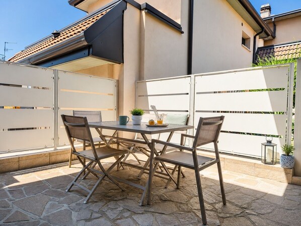 Eine Terrasse im Freien mit Tisch und Stühlen, einem Blumentopf und einer kleinen Laterne.