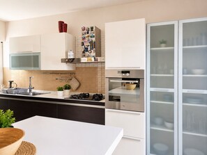 A modern kitchen with a gas stove, oven, and a refrigerator with glass doors. - La Casa di Ale By Case al Lago (Lonato)