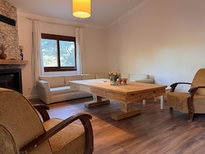 A living room with a wooden coffee table, white sofa, and two armchairs.
