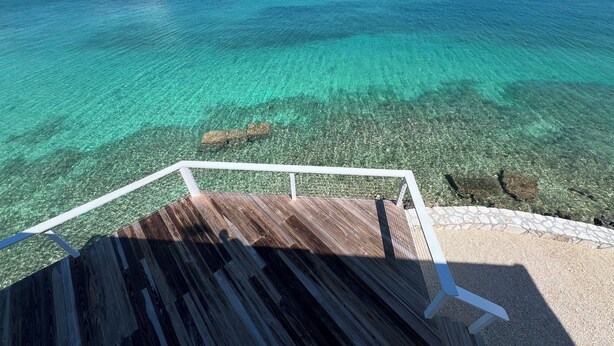 Una terraza de madera con baranda blanca que da a aguas turquesas cristalinas.
