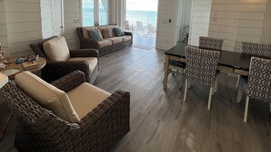 Amplia sala de estar con muebles de mimbre, ventilador de techo y vistas al exterior.