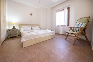 A bedroom with a bed, a nightstand, a chair, and a window with curtains. - Cozy Flat with a Lovely View in Bodrum near Beach (Bodrum)