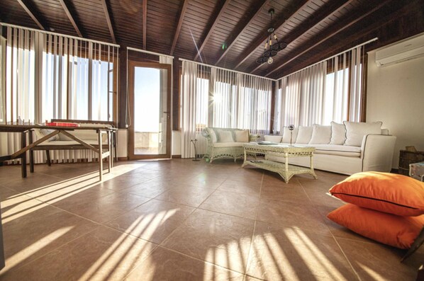 A spacious living room with a high ceiling, a sofa, a coffee table, and a dining table. - Cozy Flat with a Lovely View in Bodrum near Beach (Bodrum)