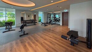 A spacious gym with various exercise equipment, large windows, and a wooden floor. - Aesthetic 1 Bed l Overlooking Marina City Skyline (Dubai)