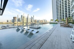 Ein Pool auf dem Dach mit Blick auf die Stadtlandschaft, Liegestühle und ein Hochhaus im Hintergrund.