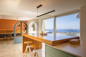 Eine moderne Küche mit einer großen Kochinsel, Barhocker und Meerblick.