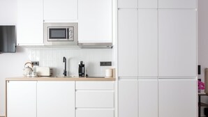 Een moderne keuken met witte kasten, een magnetron, een koffiezetapparaat en een spoelbak.
