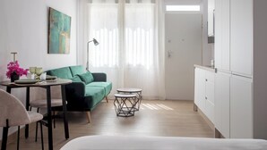 Een moderne kamer met een groene bank, een eettafel met stoelen, een ronde salontafel en een kast.