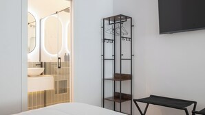 Een moderne badkamer met een douche met glazen wand, een wit wastafelmeubel en een spiegel met een ronde omlijsting.