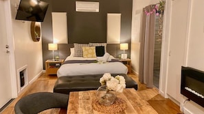 Un dormitorio moderno con cama, lámparas de noche, televisor y un jarrón decorativo.
