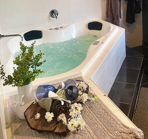 Eine Badewanne mit Pflanze, Dekoration und einem Teppich mit Struktur.