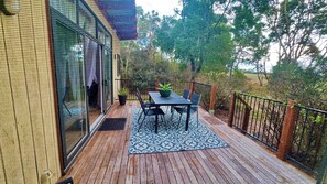 Eine überdachte Terrasse im Freien mit Tisch und Stühlen, einem Blumentopf und Blick auf ein Haus.